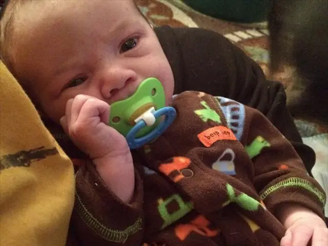 This picture looks like a human holding a baby and I can see a nipple into baby's mouth.