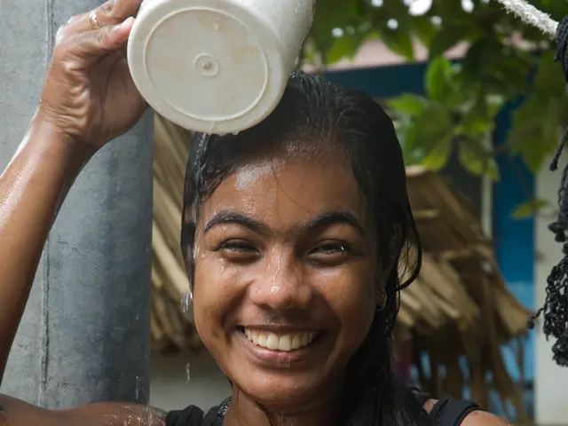In this image I can see there is a woman standing and she is holding a mug of water and laughing....