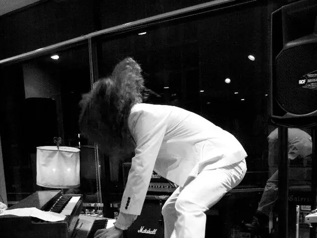 In this picture there is a man wearing white color suit is jumping in the air and playing the...